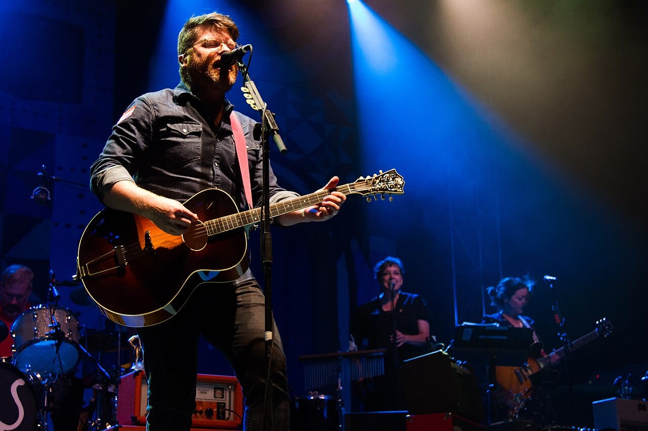 Colin Meloy, lead singer of the Portland band the Decemberists plays guitar and sings under blue spotlights.