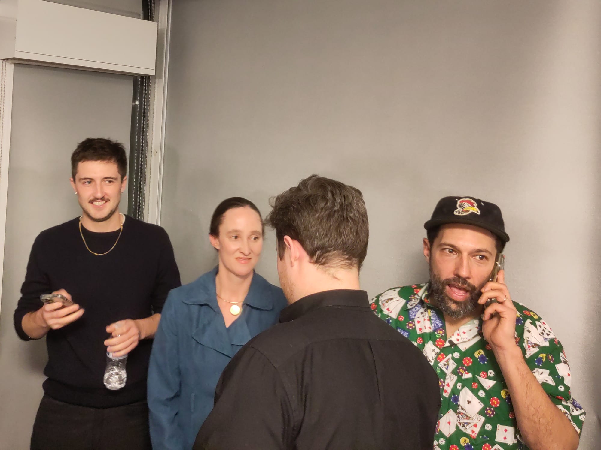 Katie Wilson stands next to staff talking on and checking phones.