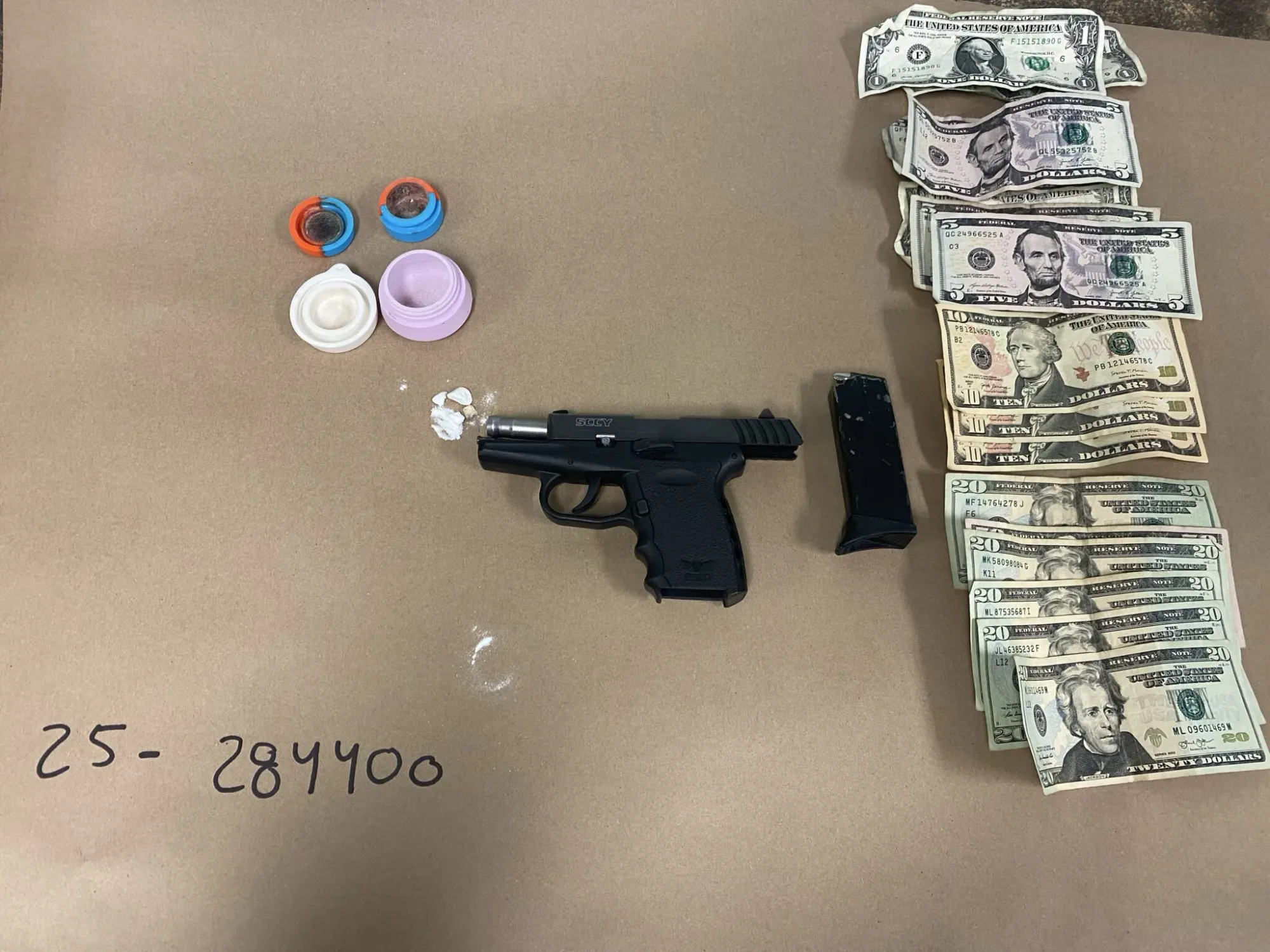 An police evidence photo with a pistol, small amount of drugs and a couple hundred dollars in cash