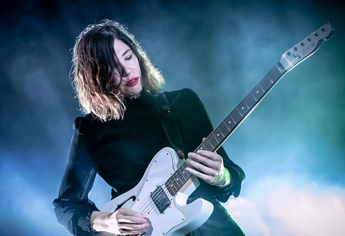 Carrie Brownstein play electric guitar on stage.