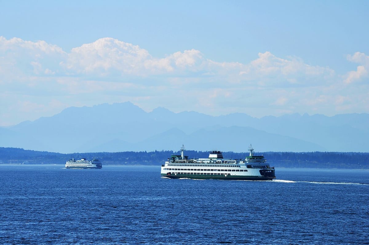 Two Washington state ferries cross Puget Sound with the Olympic mountains in the background.