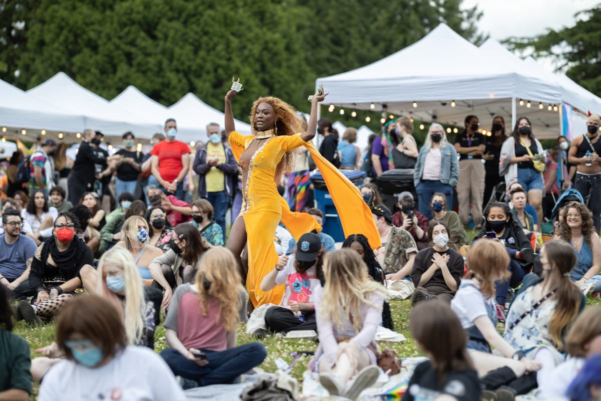 In the midst of people sitting in Seattle's Volunteer park, a Black drag performer in a bold yellow dress dances.