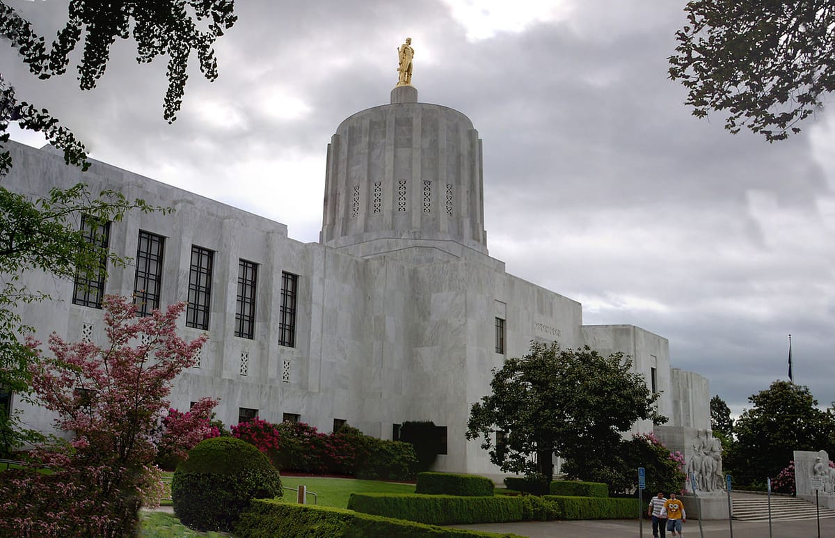 The Oregon capitol building in Salem, with several people walking in the foreground and a cloudy sky behind.
