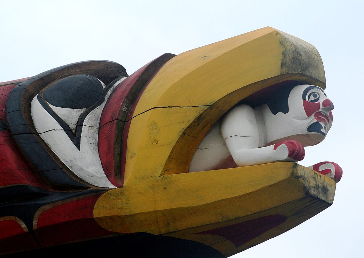Detail of a totem showing a person inside the beak of a large eagle.