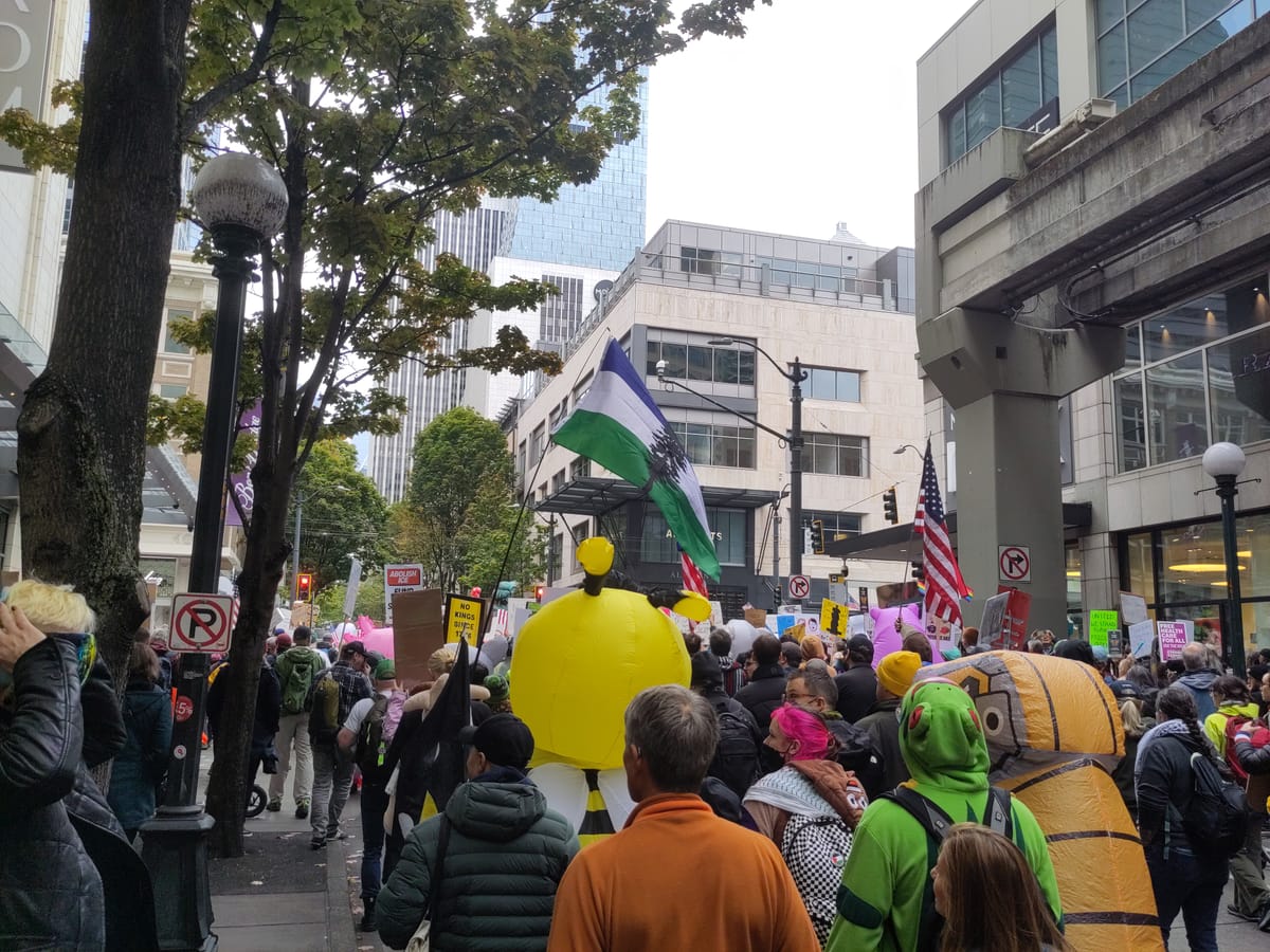 People march in downtown Seattle wearing inflatable costumes and flying a Cascadia flag.