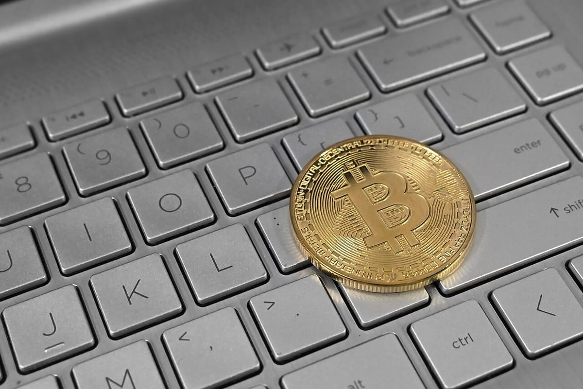 A physical Bitcoin token sits on a computer keyboard.
