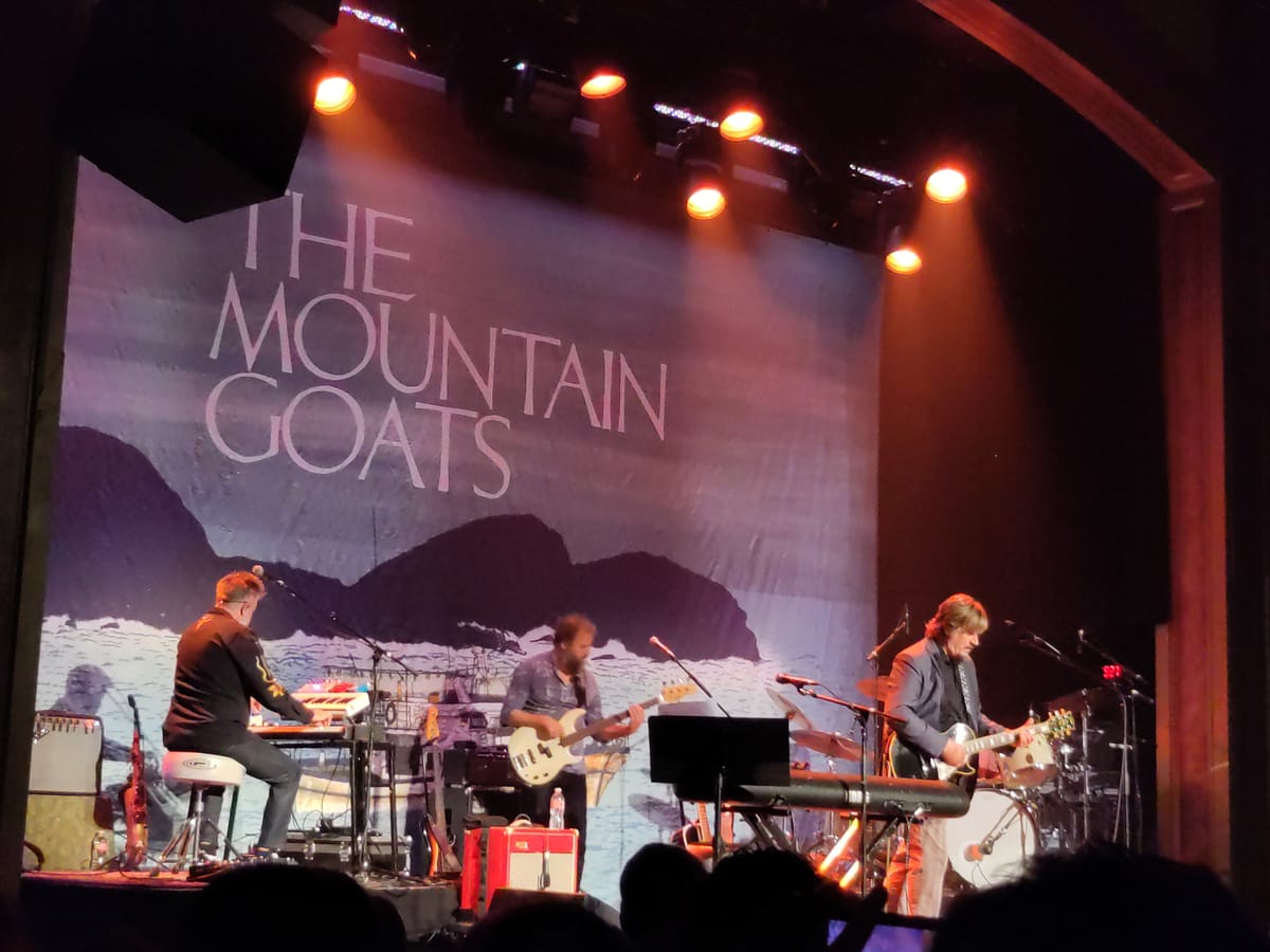 The Mountain Goats perform on stage at Seattle's Neptune theater, with members playing guitar, base, and keyboard