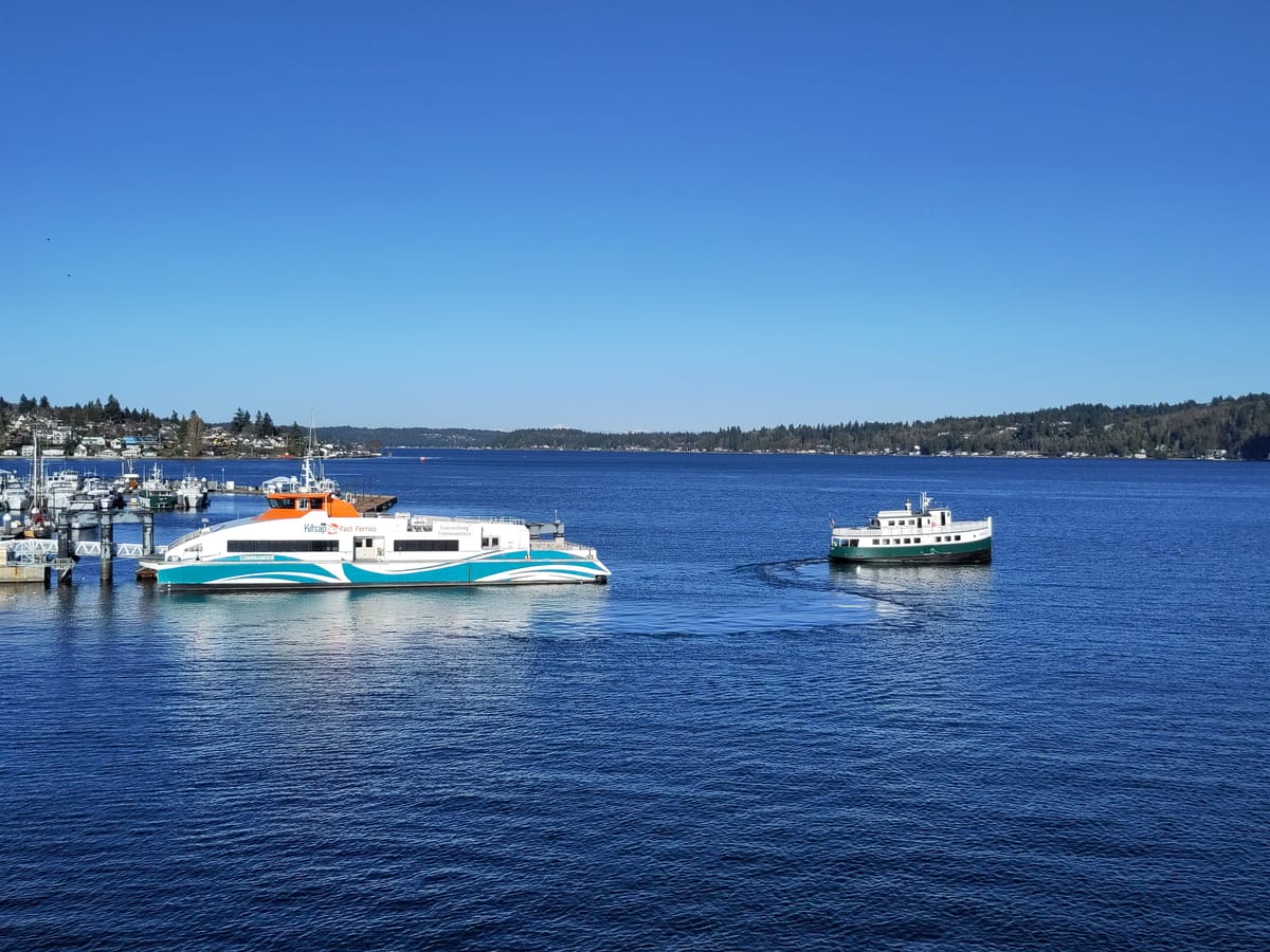 A modern passenger ferry and a tiny older diesel-driven ferry seen on Puget Sound