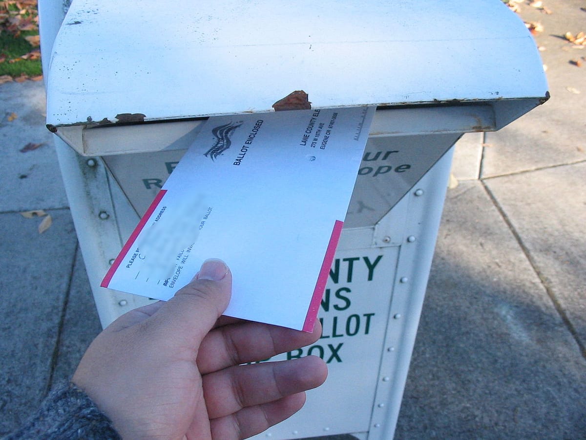 A voter puts a ballot in a box.