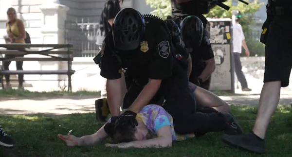 A Seattle Police Officer forcefully straddles and arrests someone wearing tie dye at a religious right wing protest in Seattle.