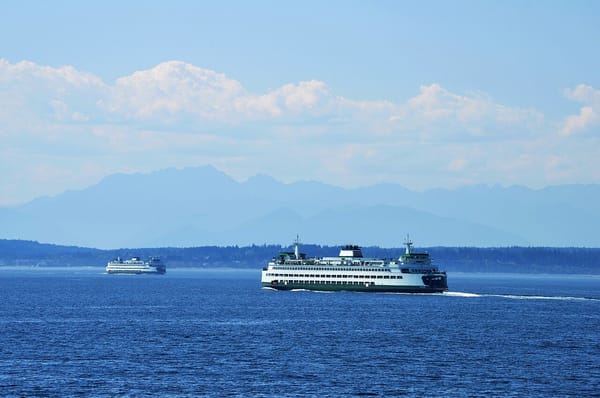 Two Washington state ferries cross Puget Sound with the Olympic mountains in the background.