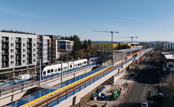 A light rail train enters a news Link station in Redmond Washington with apartments under construction in the background.