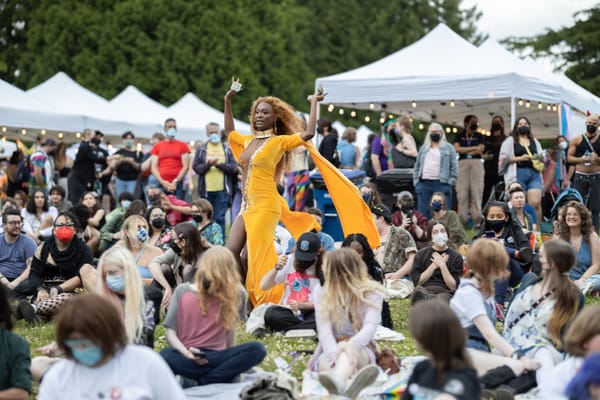 In the midst of people sitting in Seattle's Volunteer park, a Black drag performer in a bold yellow dress dances.