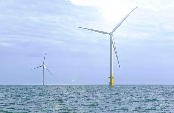 Two large wind turbines in the ocean.