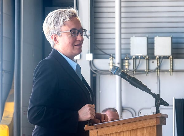 Oregon governor Tina Kotek stands at a podium and speaks into a microphone.