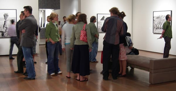 A group of people observe black and white photos in a gallery