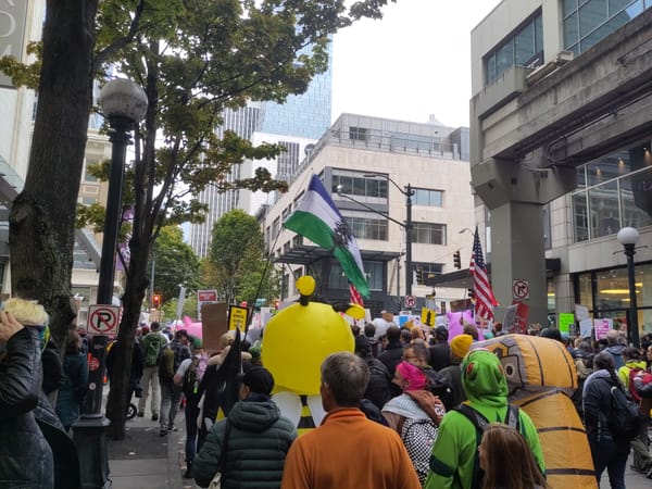 People march in downtown Seattle wearing inflatable costumes and flying a Cascadia flag.