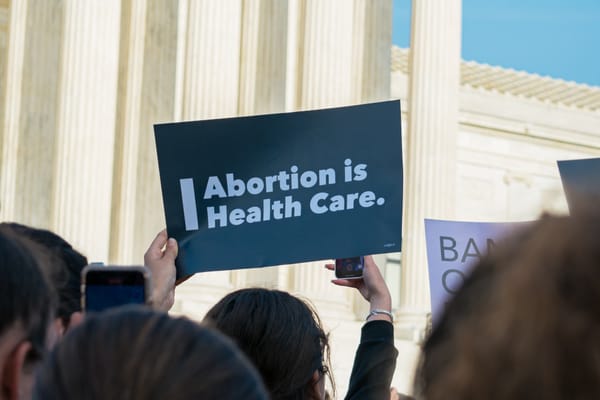 A protester in front of a judicial building holds a sign that read Abortion is Health Care
