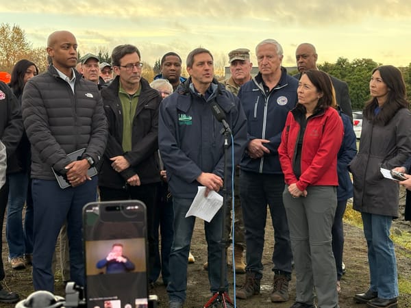 local leader gather in front of a microphone while a phone shows sign language interpretatoin