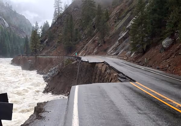 A section of highway is washed away next to a raging whitewater river