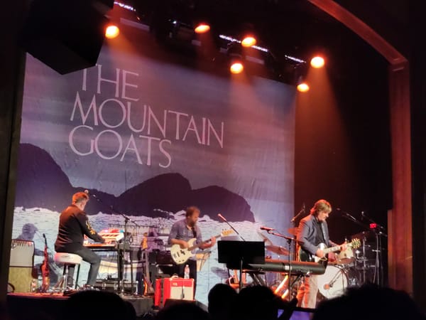 The Mountain Goats perform on stage at Seattle's Neptune theater, with members playing guitar, base, and keyboard