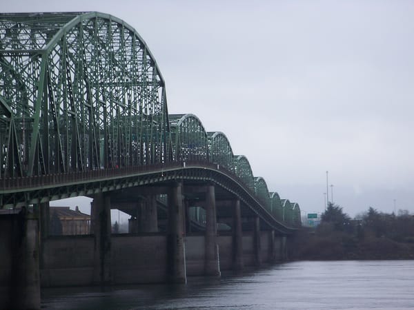 A large tressle bridge over a river with fog in the background.