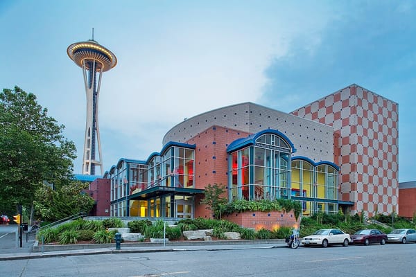 The colorful facade of a theater building with the Space Needle lit up in the background