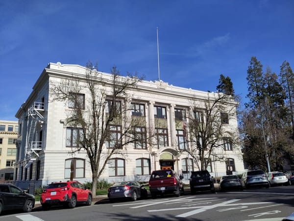 The Oregon supreme court building with a blue sky in the background and cars parked in front