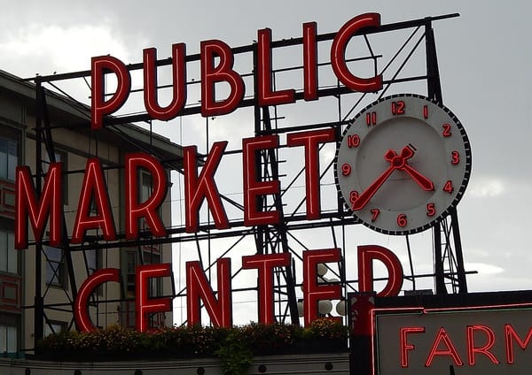 A large neon sign that says PUBLIC MARKET CENTER and a clock at 4:38.